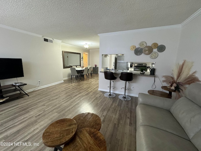 living room with a textured ceiling, wood-type flooring, and crown molding