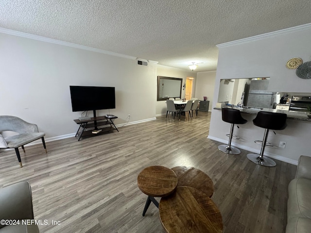 living room featuring a textured ceiling, crown molding, and hardwood / wood-style floors