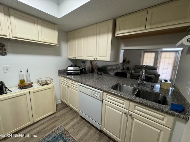 kitchen with dark hardwood / wood-style flooring, white dishwasher, a skylight, cream cabinets, and sink