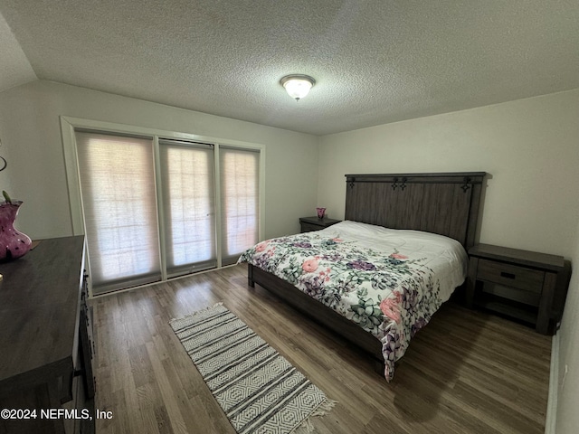 bedroom with lofted ceiling, a textured ceiling, and hardwood / wood-style flooring