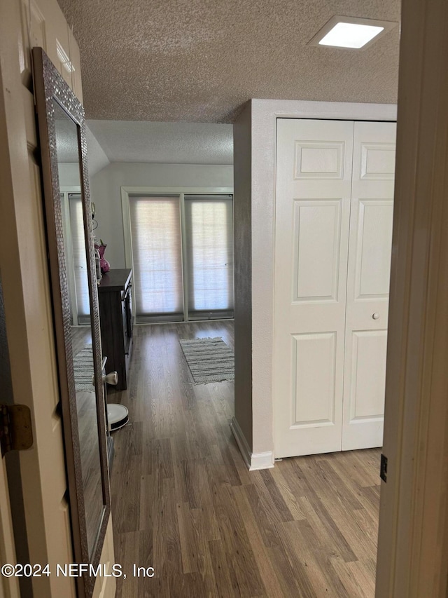 hallway with a textured ceiling and wood-type flooring