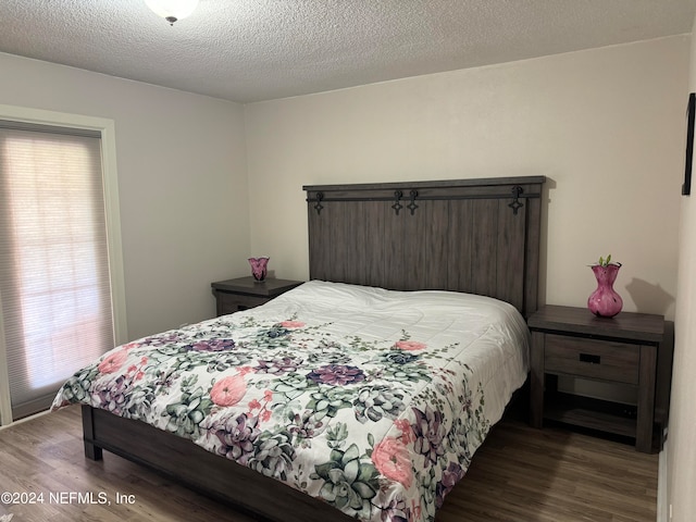 bedroom featuring a textured ceiling and dark hardwood / wood-style floors