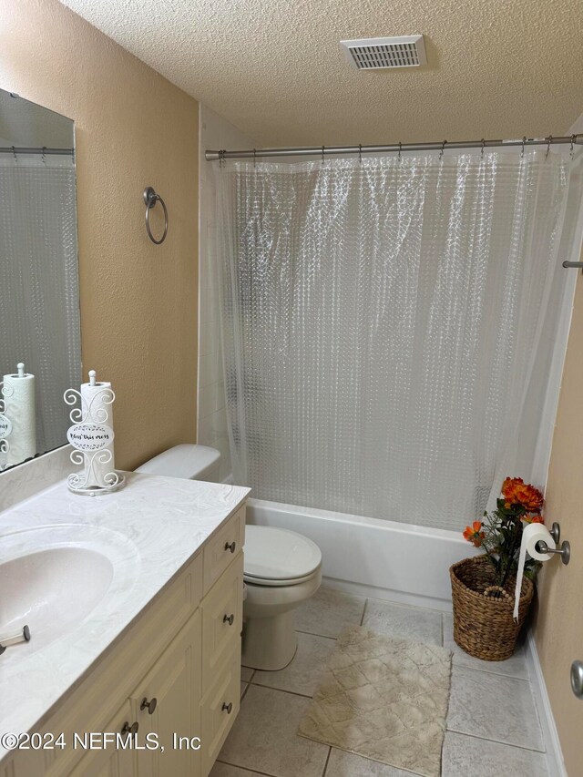 full bathroom featuring shower / bathtub combination with curtain, vanity, a textured ceiling, toilet, and tile patterned floors