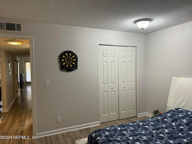 bedroom with a textured ceiling, a closet, and dark hardwood / wood-style floors