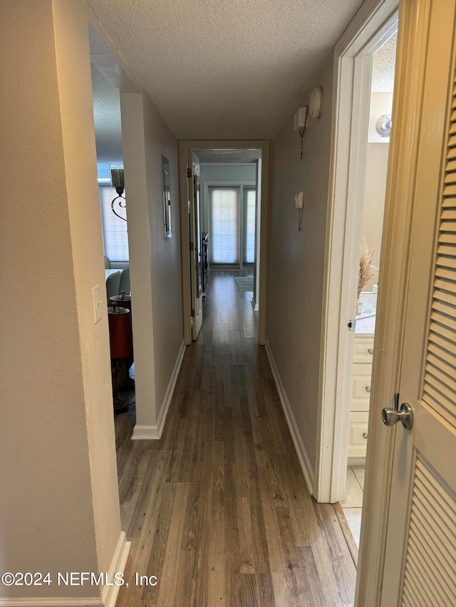 corridor featuring a textured ceiling and hardwood / wood-style flooring