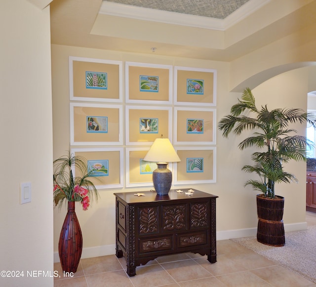 interior space featuring ornamental molding, tile patterned flooring, and a raised ceiling