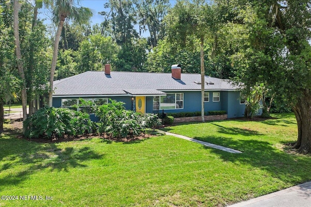 ranch-style house with a chimney and a front yard