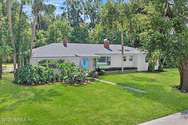 single story home featuring stucco siding, a chimney, a front yard, and a shingled roof