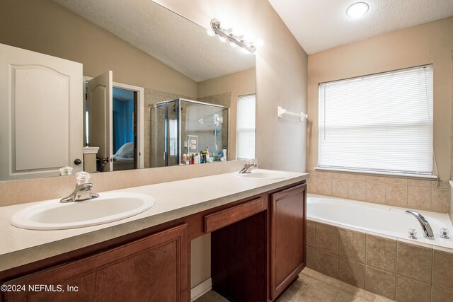 bathroom with vanity, a textured ceiling, independent shower and bath, lofted ceiling, and tile patterned flooring