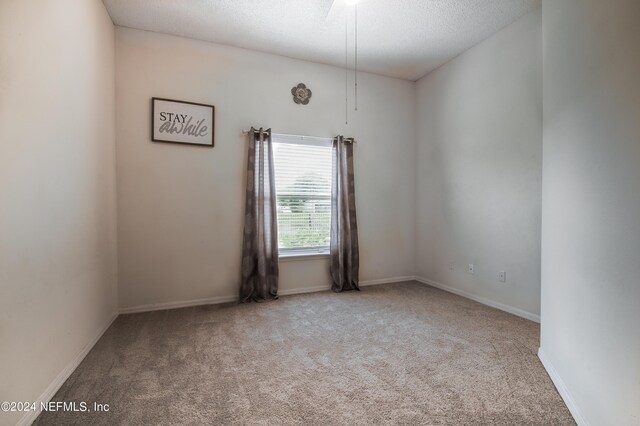 carpeted empty room featuring a textured ceiling