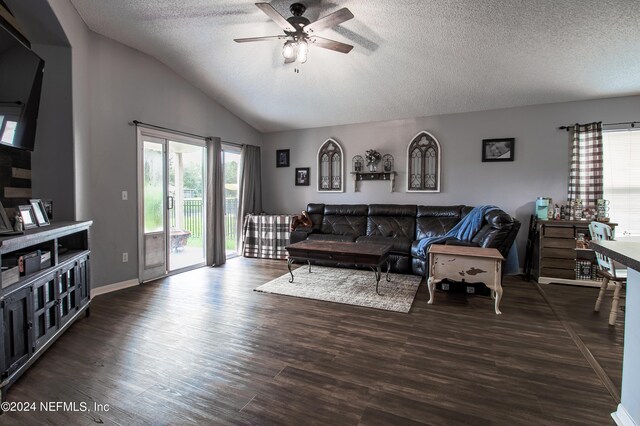 living room with ceiling fan, vaulted ceiling, a textured ceiling, and dark wood-type flooring