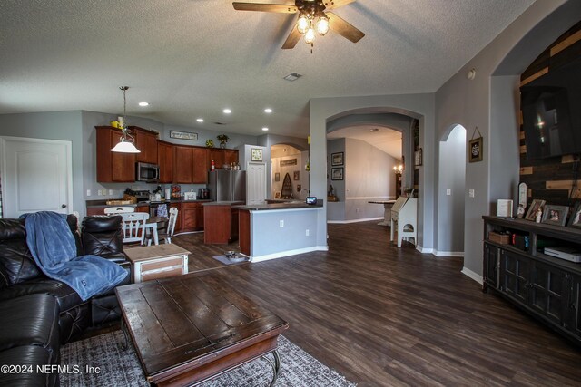 living room featuring vaulted ceiling, ceiling fan, dark wood-type flooring, and a textured ceiling