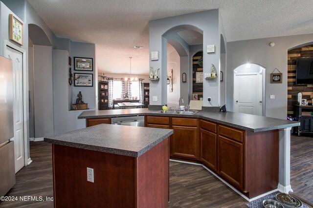 kitchen featuring a textured ceiling, kitchen peninsula, a kitchen island, and sink