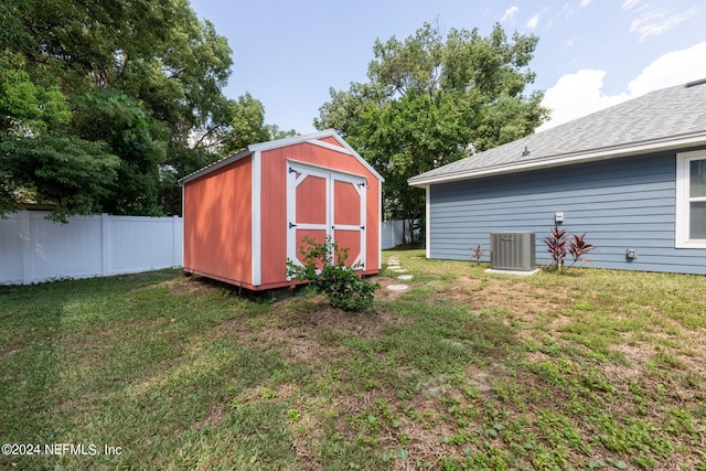 view of outdoor structure featuring central AC unit and a yard