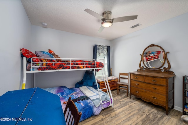 bedroom with a textured ceiling, wood-type flooring, and ceiling fan