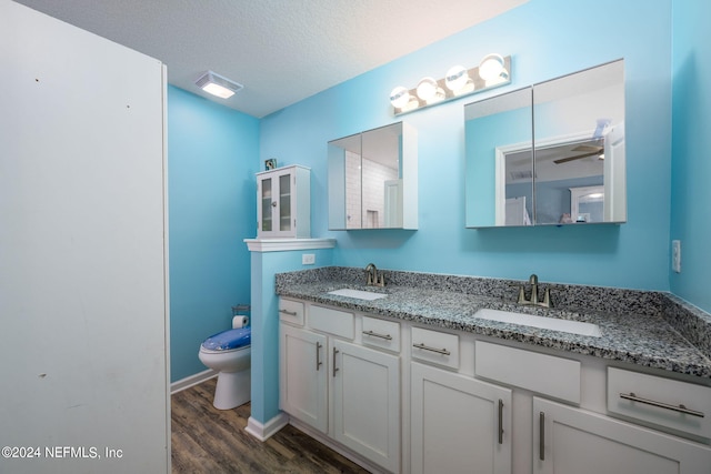 bathroom featuring a textured ceiling, hardwood / wood-style floors, ceiling fan, vanity, and toilet