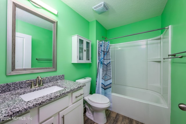 full bathroom with shower / bath combo, a textured ceiling, hardwood / wood-style floors, vanity, and toilet