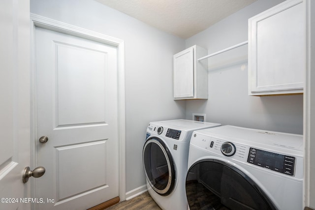 laundry room featuring a textured ceiling, dark hardwood / wood-style floors, washing machine and clothes dryer, and cabinets