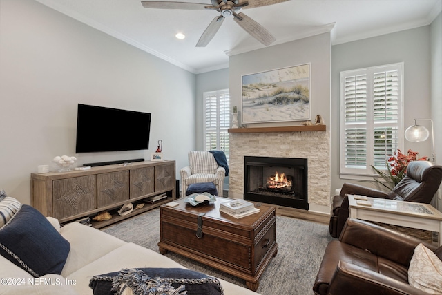 living room with a stone fireplace, ornamental molding, hardwood / wood-style floors, and ceiling fan