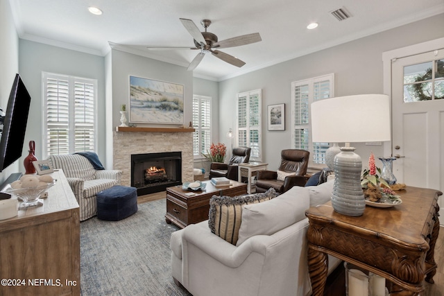 living room featuring a healthy amount of sunlight, a fireplace, ornamental molding, and ceiling fan