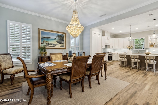 dining space with light hardwood / wood-style flooring, sink, an inviting chandelier, and crown molding