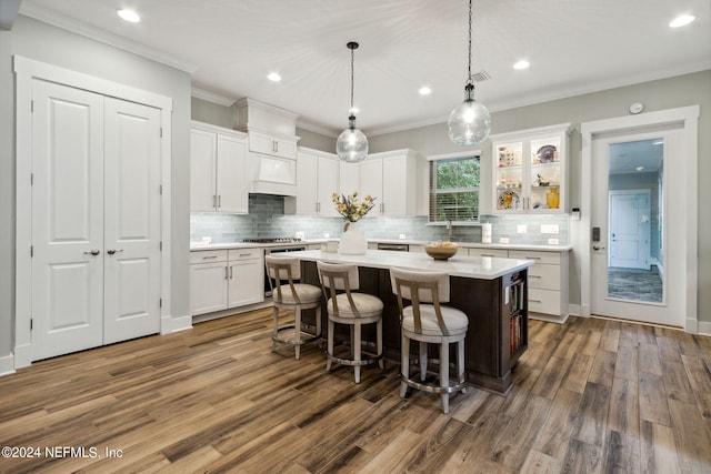 kitchen featuring white cabinets, a kitchen island, a kitchen breakfast bar, crown molding, and dark hardwood / wood-style flooring