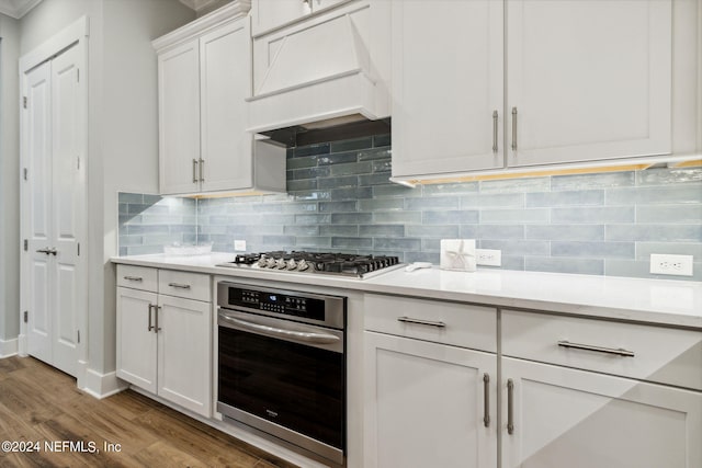 kitchen featuring white cabinetry, tasteful backsplash, stainless steel appliances, light wood-type flooring, and custom exhaust hood