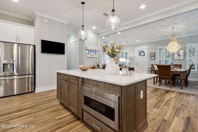 kitchen with stainless steel appliances, a chandelier, light wood-type flooring, and crown molding