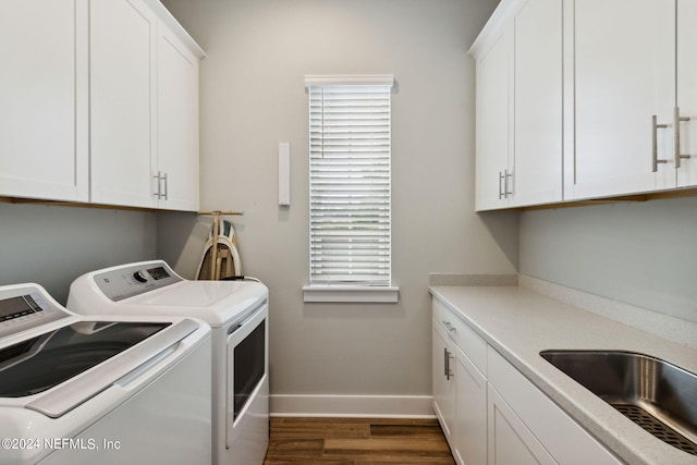 washroom featuring washing machine and clothes dryer, dark hardwood / wood-style floors, cabinets, and sink