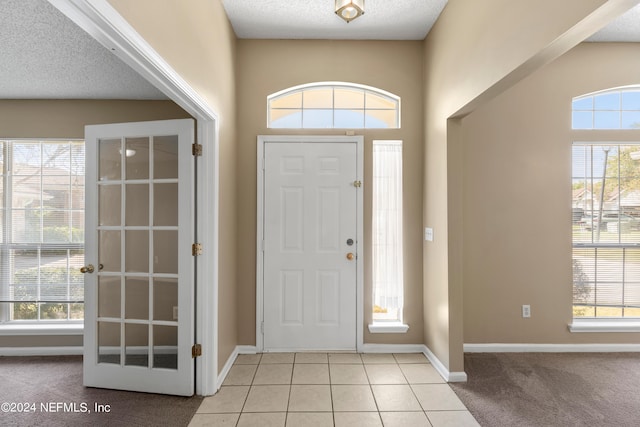 foyer entrance with a textured ceiling and light carpet