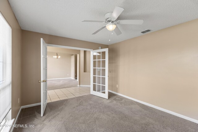 empty room featuring ceiling fan, light colored carpet, a textured ceiling, and french doors