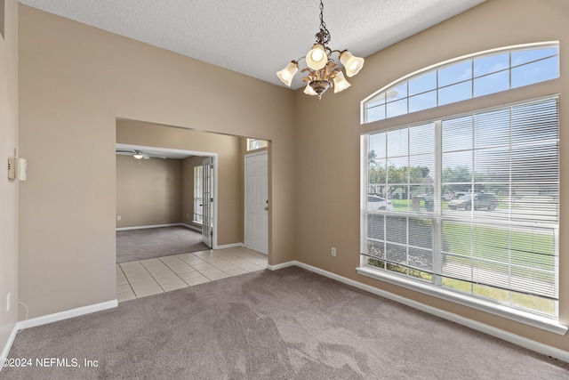 spare room with light carpet, an inviting chandelier, a textured ceiling, and a healthy amount of sunlight