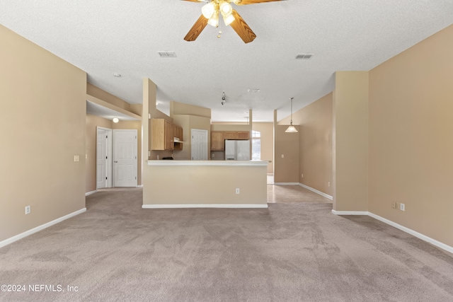 unfurnished living room with a textured ceiling, ceiling fan, and light colored carpet