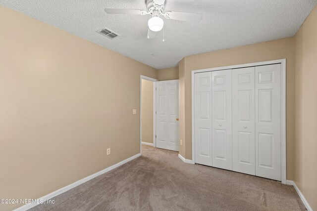 unfurnished bedroom featuring light carpet, a closet, ceiling fan, and a textured ceiling