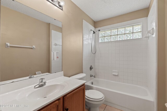 full bathroom featuring tiled shower / bath, vanity, a textured ceiling, tile patterned floors, and toilet