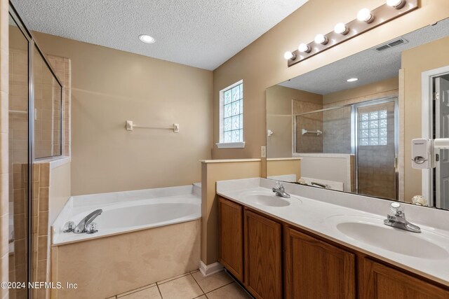 bathroom with a textured ceiling, vanity, plus walk in shower, and tile patterned floors