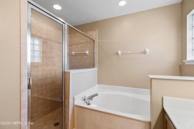 bathroom featuring plus walk in shower, a textured ceiling, and vanity