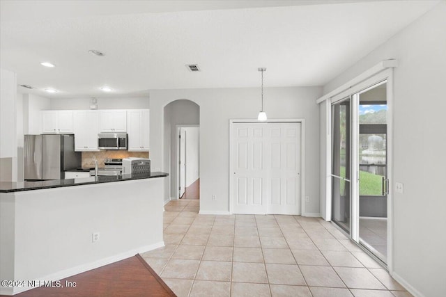 kitchen with white cabinets, hanging light fixtures, decorative backsplash, stainless steel appliances, and light tile patterned floors