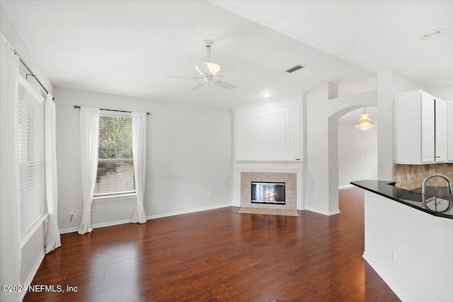 unfurnished living room featuring ceiling fan, a fireplace, and dark hardwood / wood-style flooring