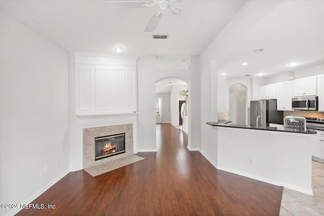 unfurnished living room with ceiling fan, light hardwood / wood-style flooring, and sink