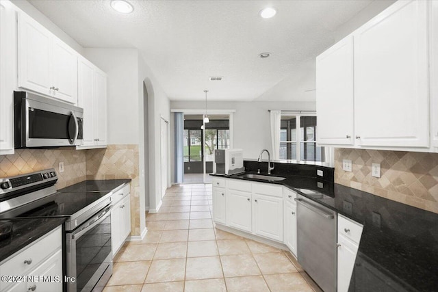 kitchen featuring white cabinets, hanging light fixtures, sink, appliances with stainless steel finishes, and decorative backsplash