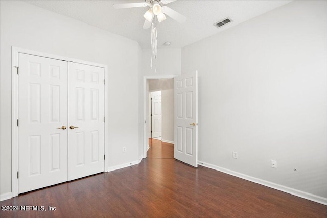 unfurnished bedroom featuring ceiling fan, a textured ceiling, a closet, and dark hardwood / wood-style flooring