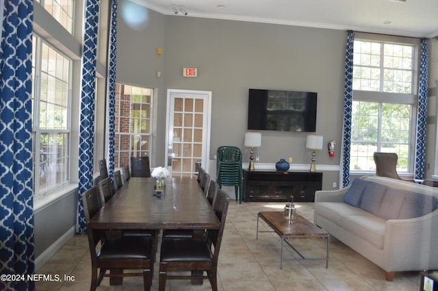 tiled dining room featuring plenty of natural light, a high ceiling, and crown molding