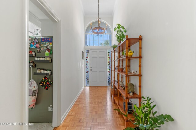 entryway featuring ornamental molding, a chandelier, and light parquet flooring