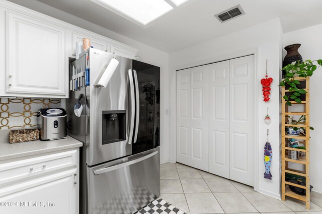 kitchen featuring white cabinets, light tile patterned flooring, and stainless steel fridge