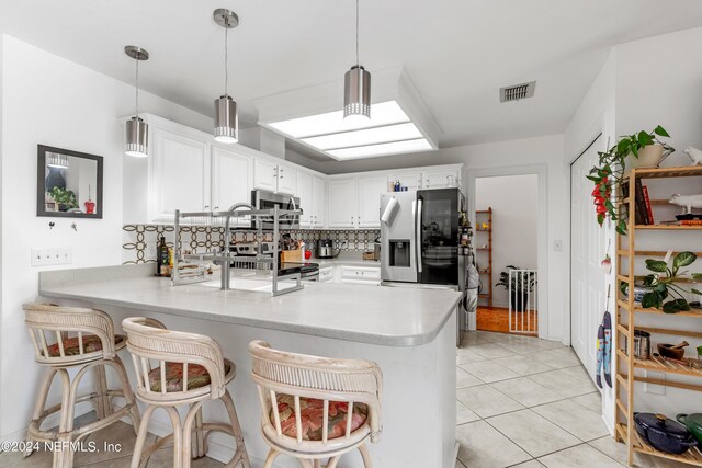 kitchen featuring kitchen peninsula, tasteful backsplash, decorative light fixtures, white cabinetry, and appliances with stainless steel finishes