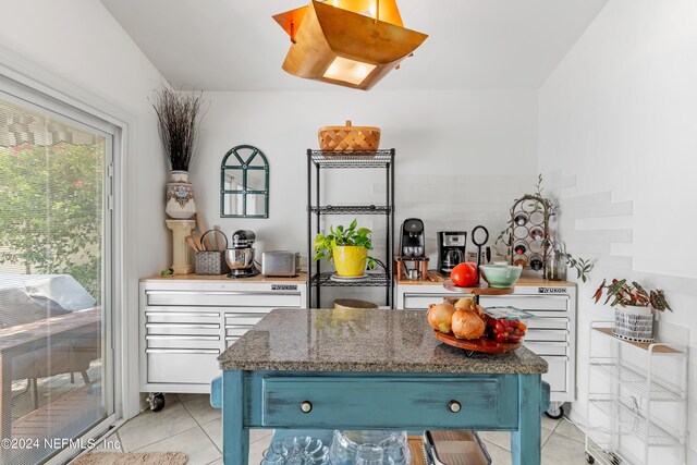 kitchen featuring dark stone counters, light tile patterned flooring, blue cabinetry, and white cabinetry