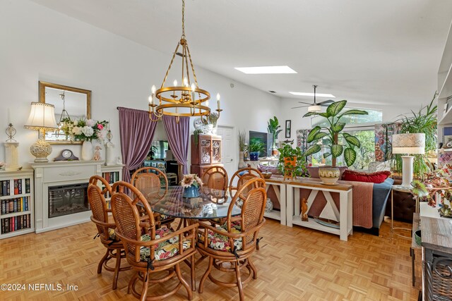 dining area featuring light parquet floors, ceiling fan with notable chandelier, and lofted ceiling with skylight