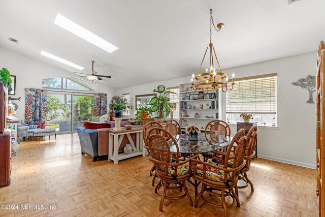 dining area with ceiling fan with notable chandelier, a wealth of natural light, light parquet floors, and vaulted ceiling with skylight