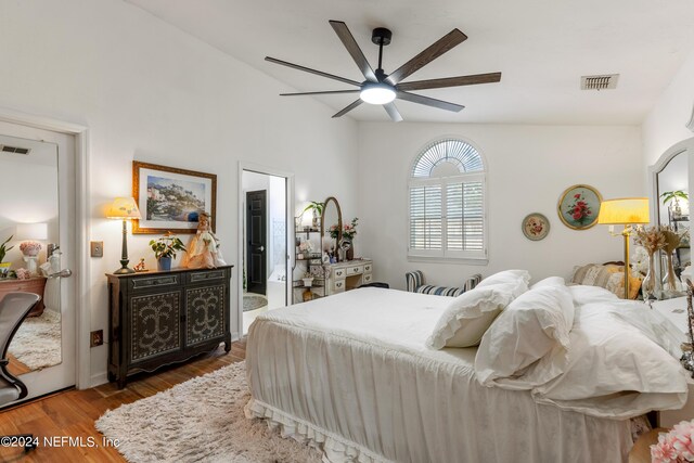 bedroom featuring lofted ceiling, connected bathroom, dark hardwood / wood-style flooring, and ceiling fan